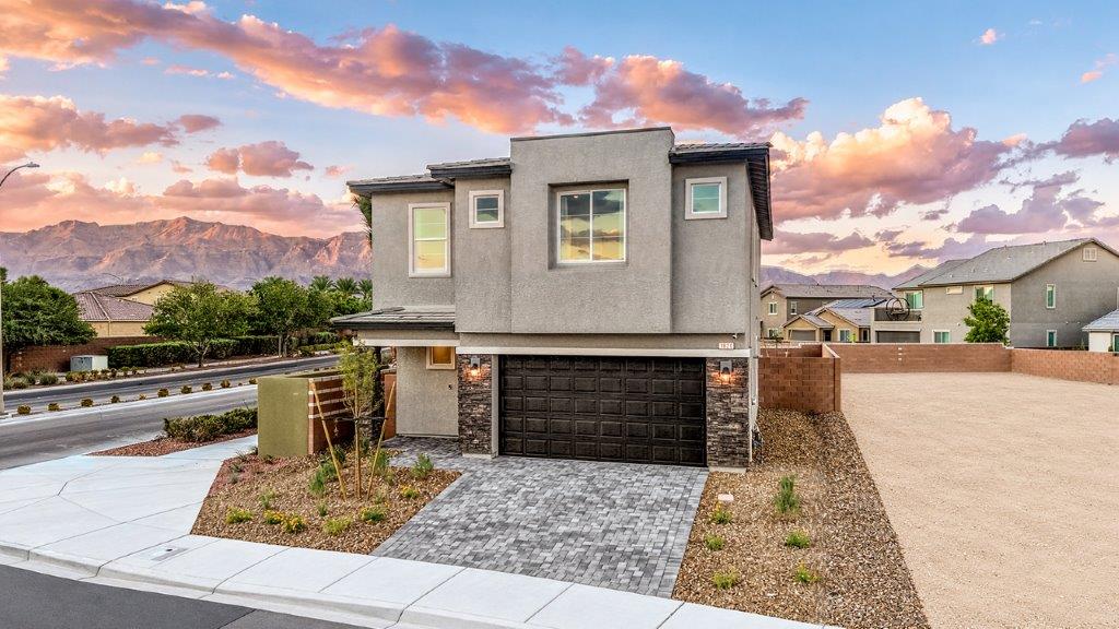 Our 2660 model home in the Serenity community with white and black exterior paint schemes, a flat tile roof, front yard landscaping, 2-car garage, and paver walkways