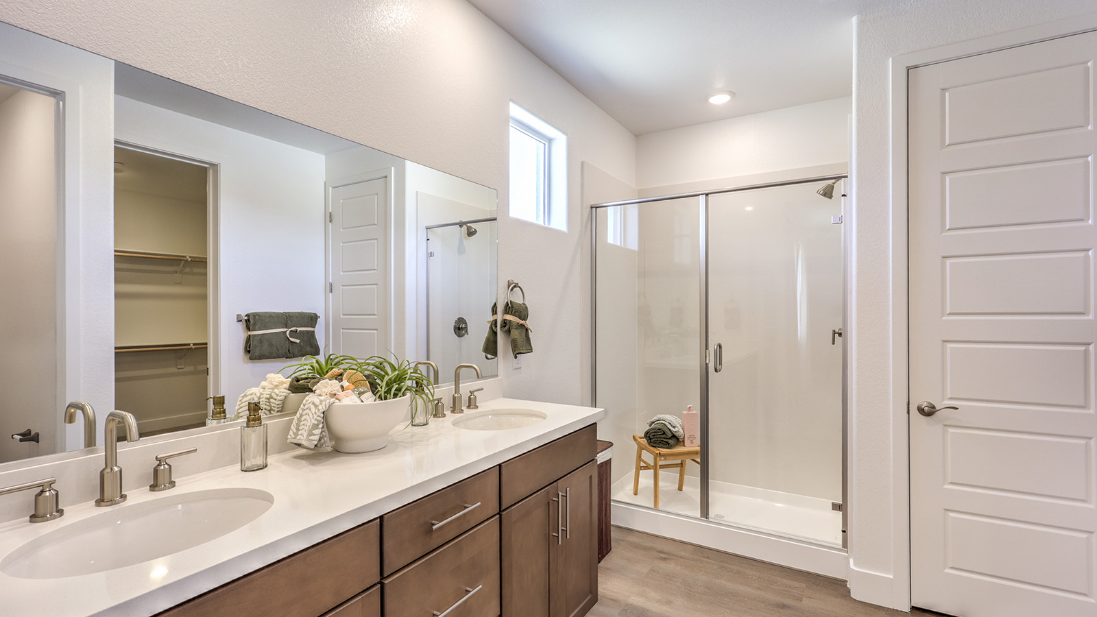 Attached to the Bedroom One Suite, our 2660 model bathroom with granite countertops at the double Bath Vanity, a walk-in shower, walk-in closet, mirror, and grey cabinets.