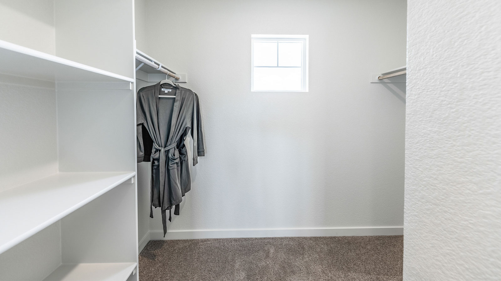 Walk-in closet with built-in shelves and a small window to let in natural light