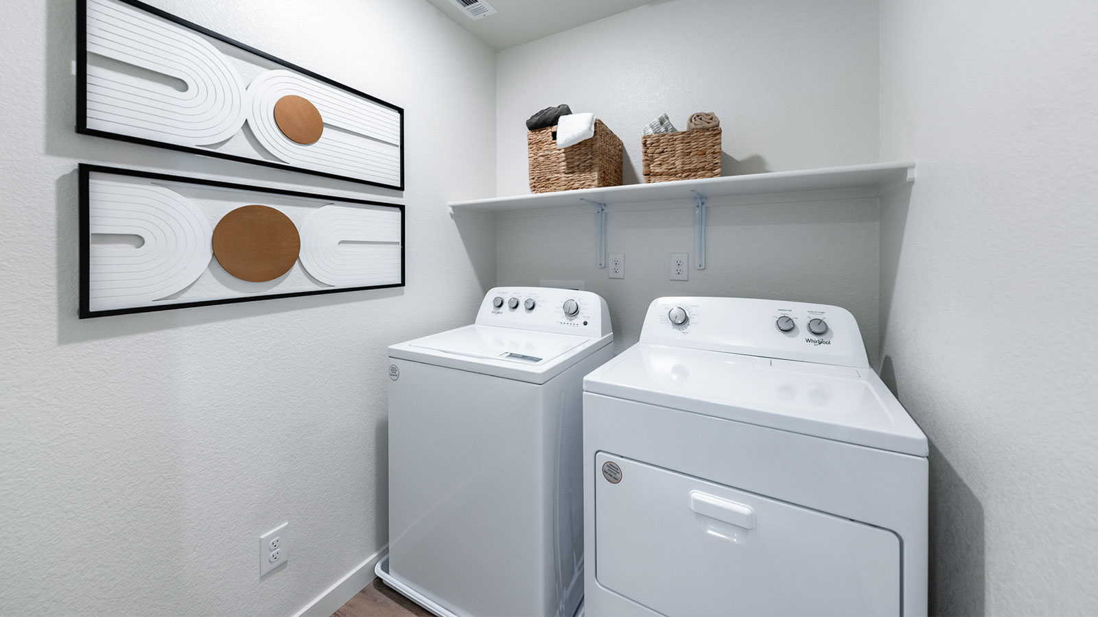 Separate laundry room with shelf above the full-sized washer and dryer