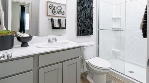 Secondary bathroom with grey cabinets and shower