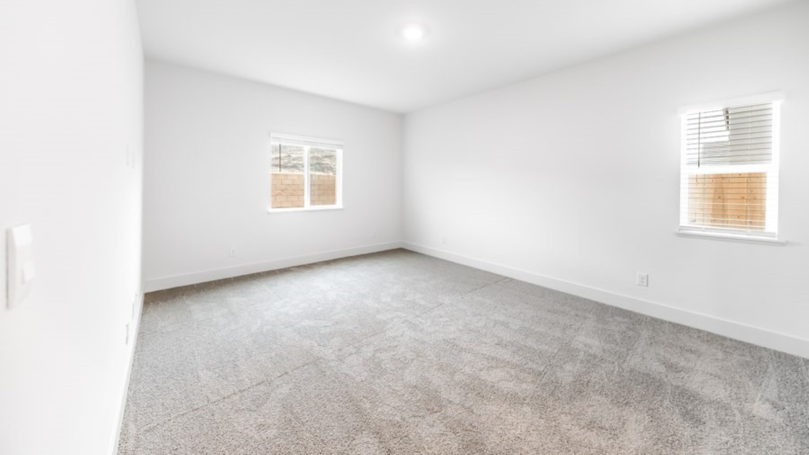 Carpeted primary bedroom with large windows and attached bathroom