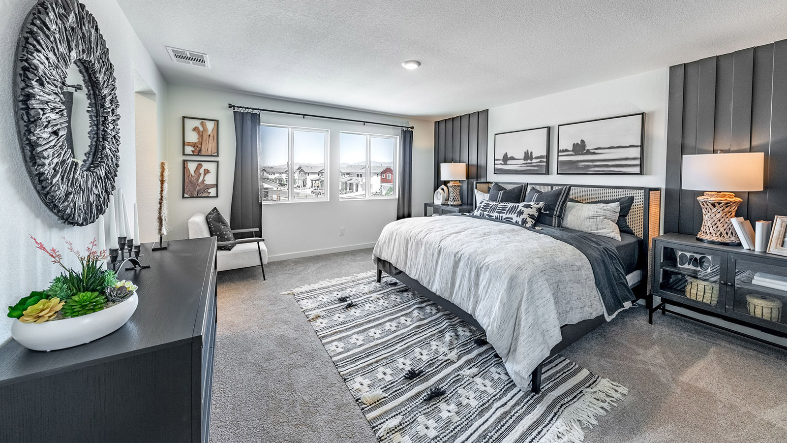 Large carpeted primary bedroom with bright windows