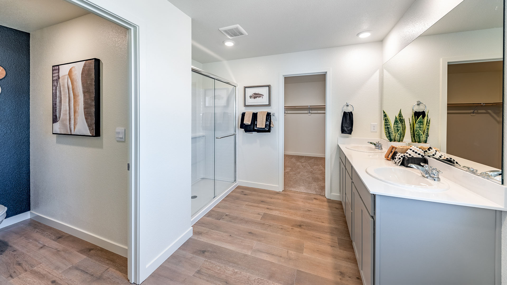 Large primary bathroom with double vanity, walk-in shower, and walk-in closet