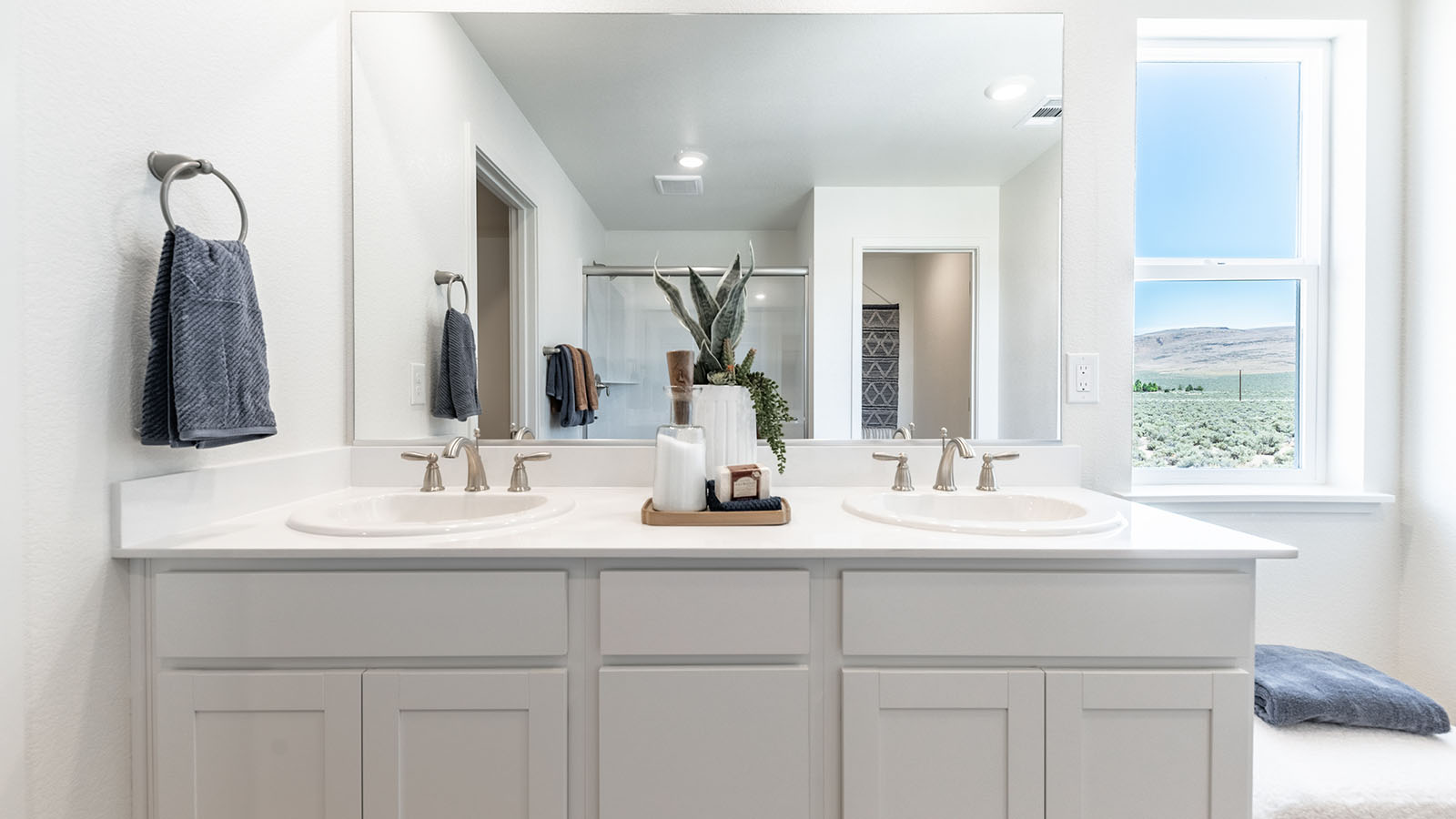 Primary bathroom with double vanity and large window to keep the room bright