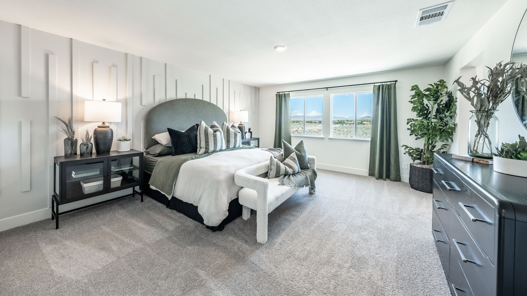 Large primary bedroom with carpeted floor and big windows to let in natural light