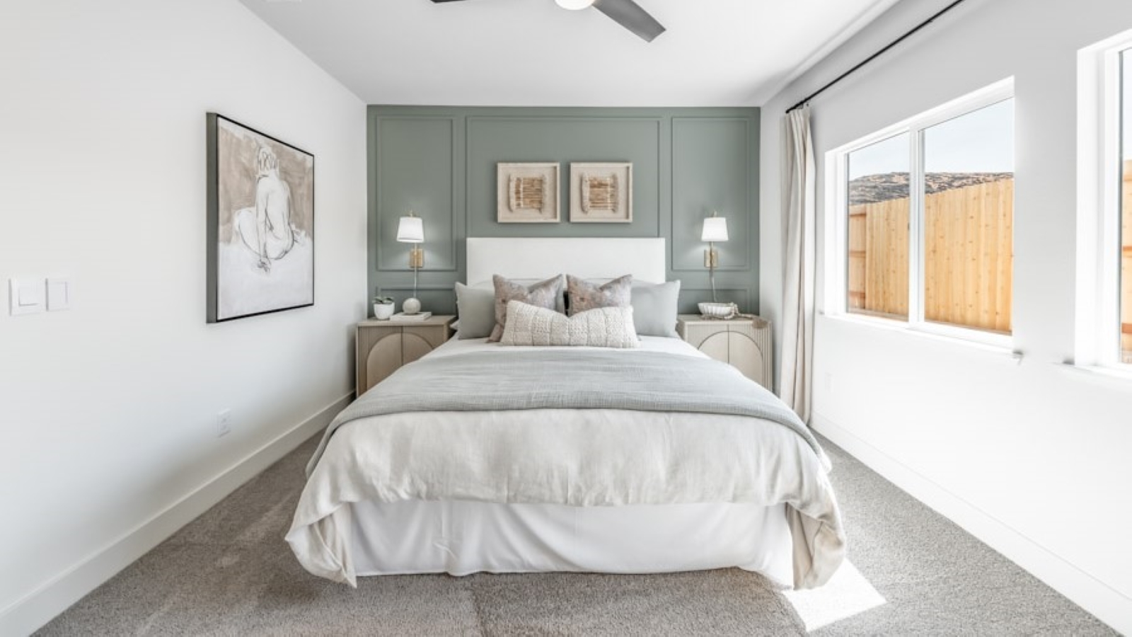 Bright primary bedroom with two windows and carpeted floors