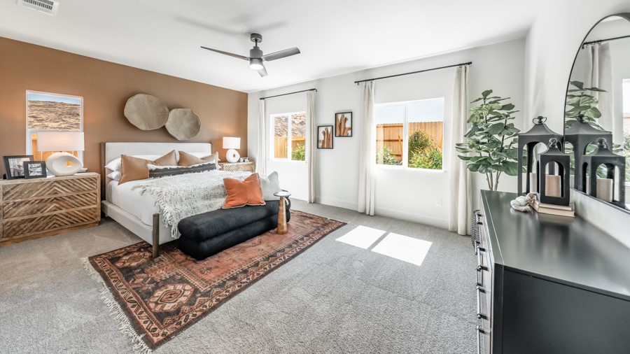 Large primary bedroom on the first floor with carpeted floor and big windows to let in natural light