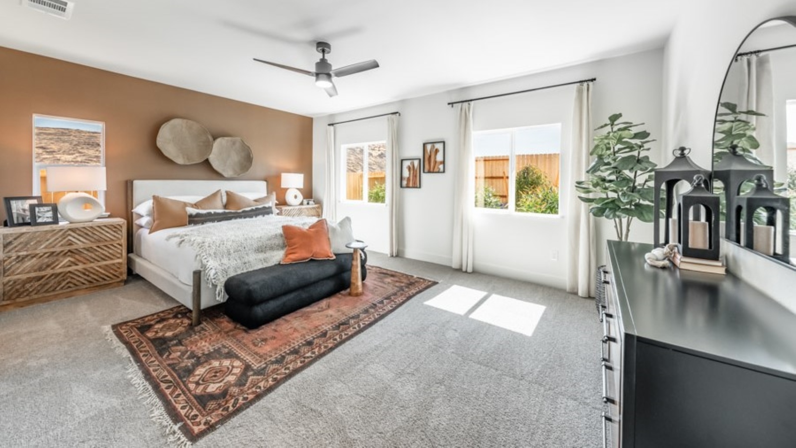 Large primary bedroom on the first floor with carpeted floor and big windows to let in natural light
