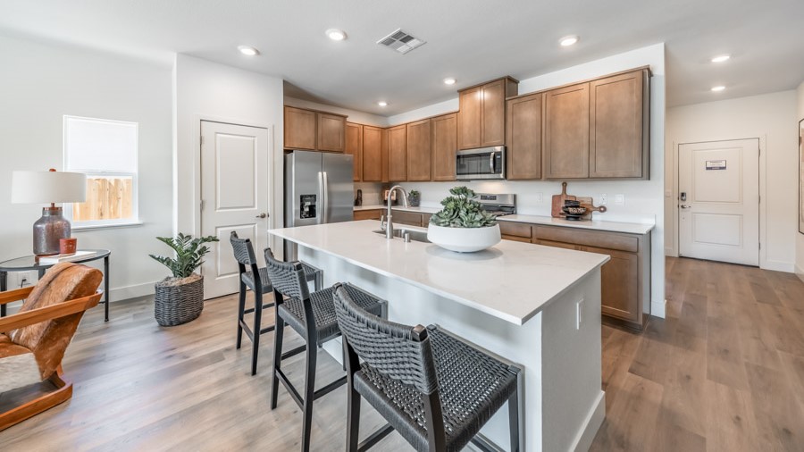 Large kitchen island with space for three barstools separating kitchen area from the rest of the open-concept first floor