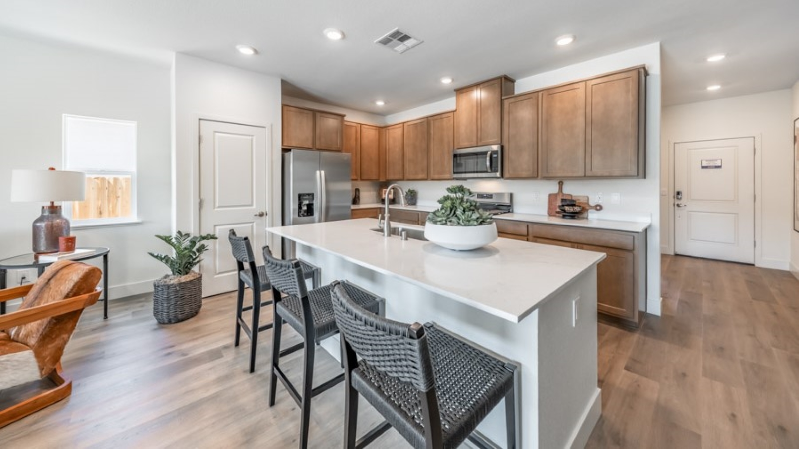 Large kitchen island with space for three barstools separating kitchen area from the rest of the open-concept first floor