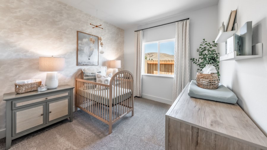 Secondary bedroom decorated as a nursery with carpeted floors