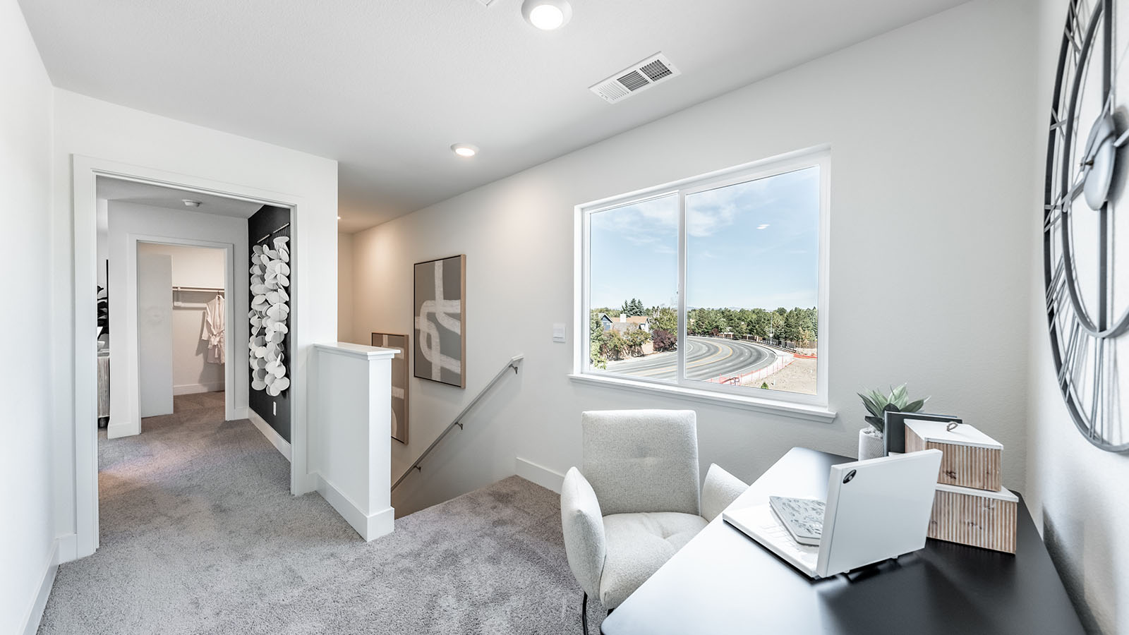 Second floor carpeted loft leading into bedrooms, with a space for a desk
