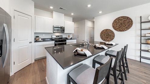 Modern kitchen with large pantry, white shaker-style cabinets, and kitchen island with enough space for three barstools