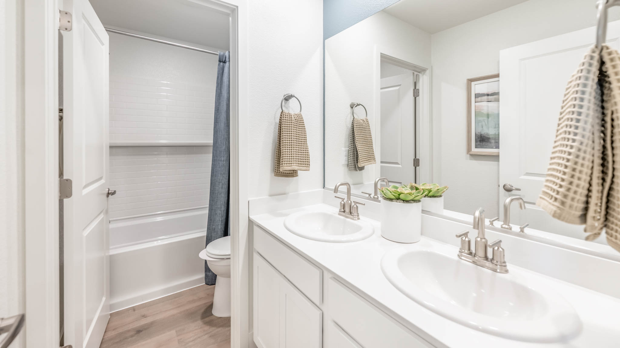 Secondary bathroom with a dual vanity with a separate room for the toilet and shower tub combo