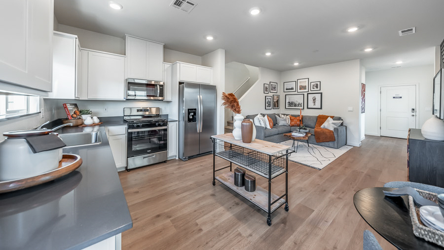 Phoenix's Denali model home's kitchen boasts white, shaker-style cabinetry, stainless steel applicances, a window over the kitchen sink, and easy access to the adjoining living room.