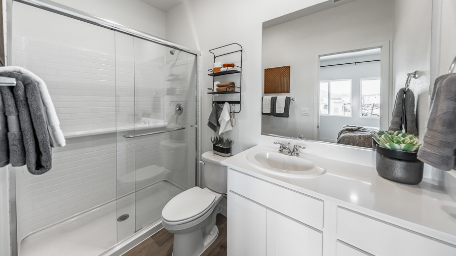 Primary bathroom in the Denali model home features white, shaker-style cabinetry, white countertop with one sink, and a walk-in shower with sliding glass doors.
