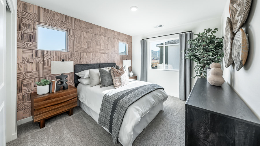 Secondary bedroom in the Denali model home has a queen bed flanked by two nightstands in front of an accent wall with a dresser on the opposite wall.
