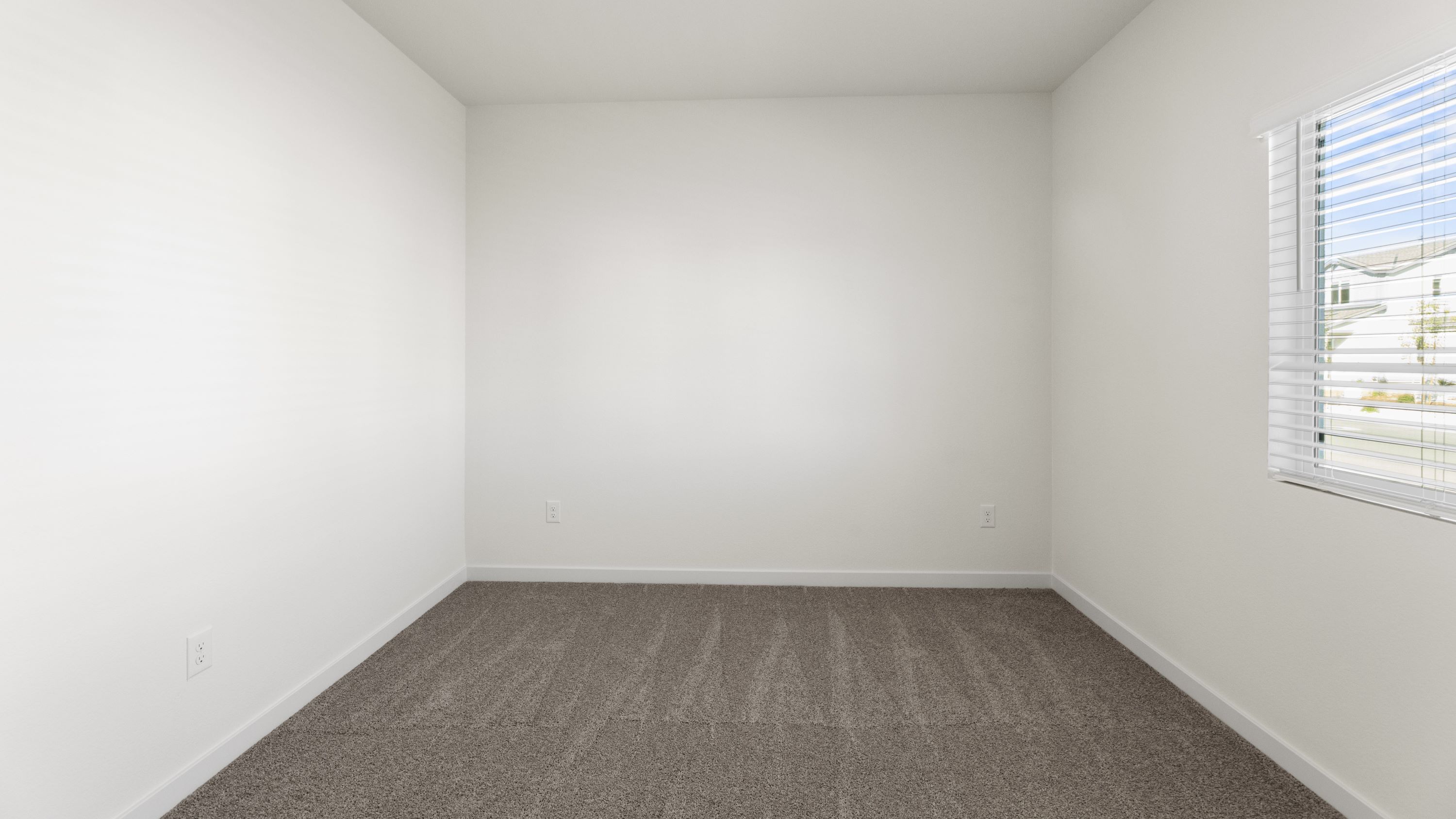 Bedroom with large window letting in bright light and carpeted floors