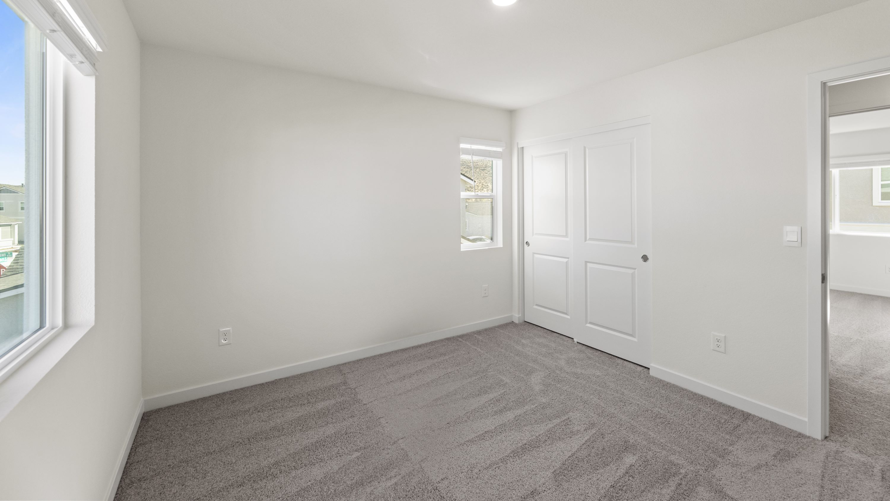 Bedroom with large window letting in bright light and carpeted floors