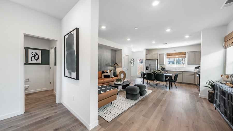 Looking from the front of the home into the open-concept living, dining, and kitchen with a view of the powder bathroom.