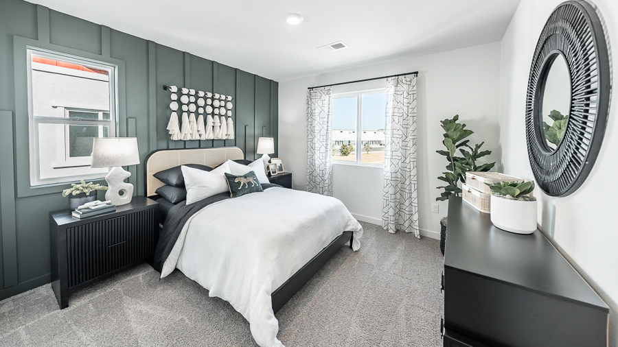 Primary bedroom with a large bed, two nightstands, a dresser, and a stunning accent wall with carpentry accents in Phoenix's Saguaro model home.