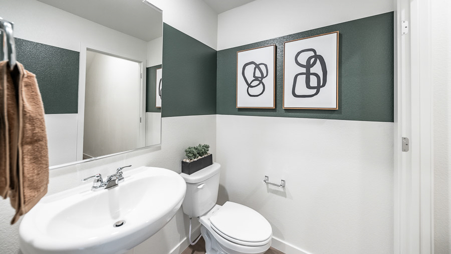Powder bathroom with a pedestal sink and accent stripe painted on the wall with simple artwork.