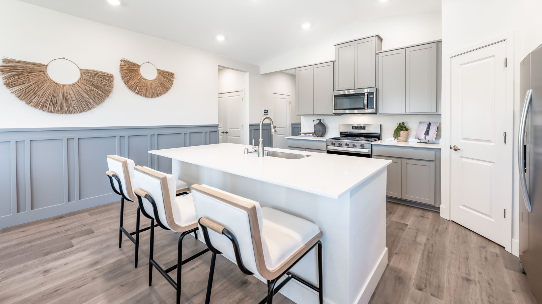 Kitchen island with 3 barstools separating it from the great room