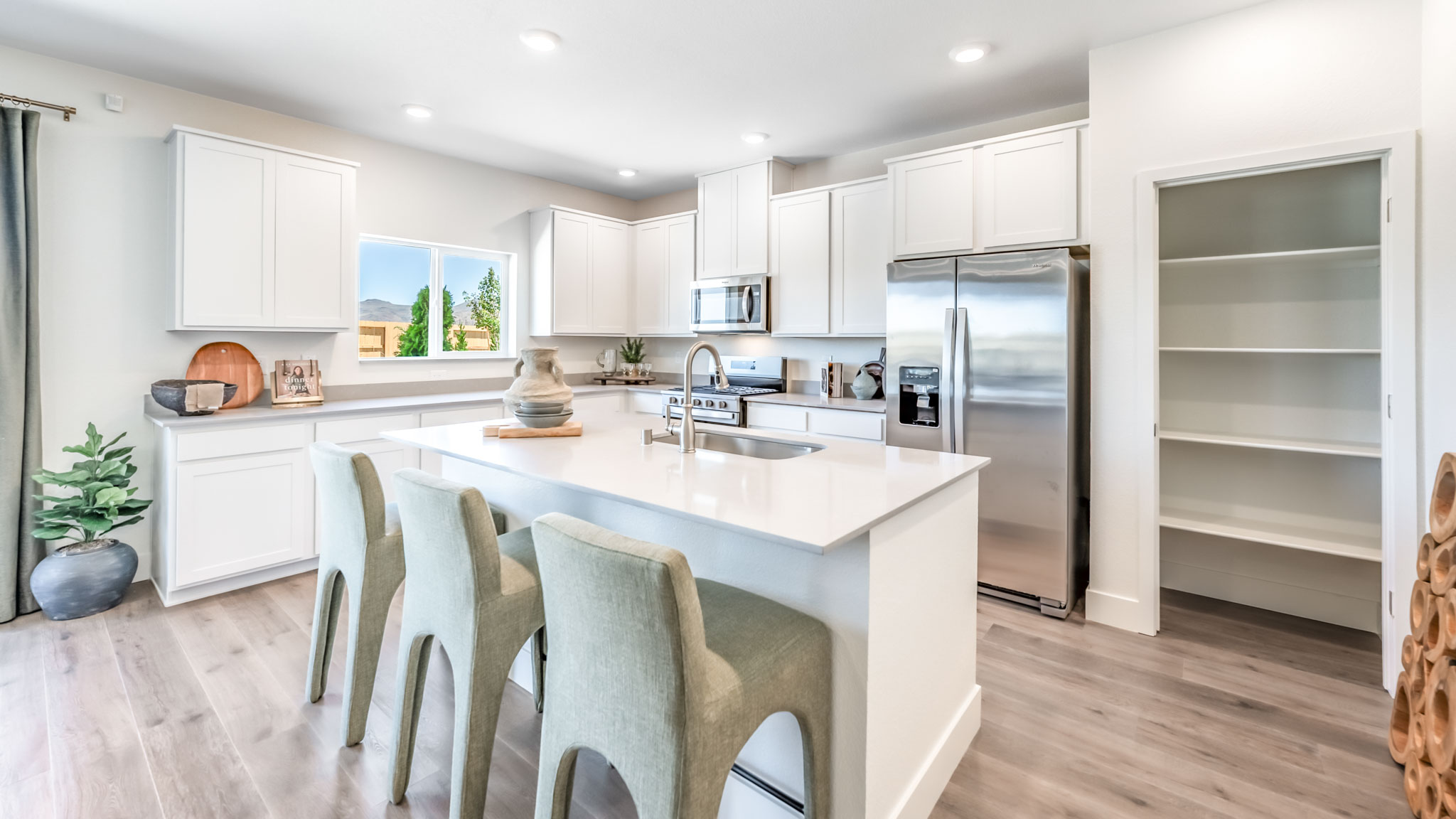 Large kitchen island with space for three barstools separating kitchen area from the rest of the open-concept first floor