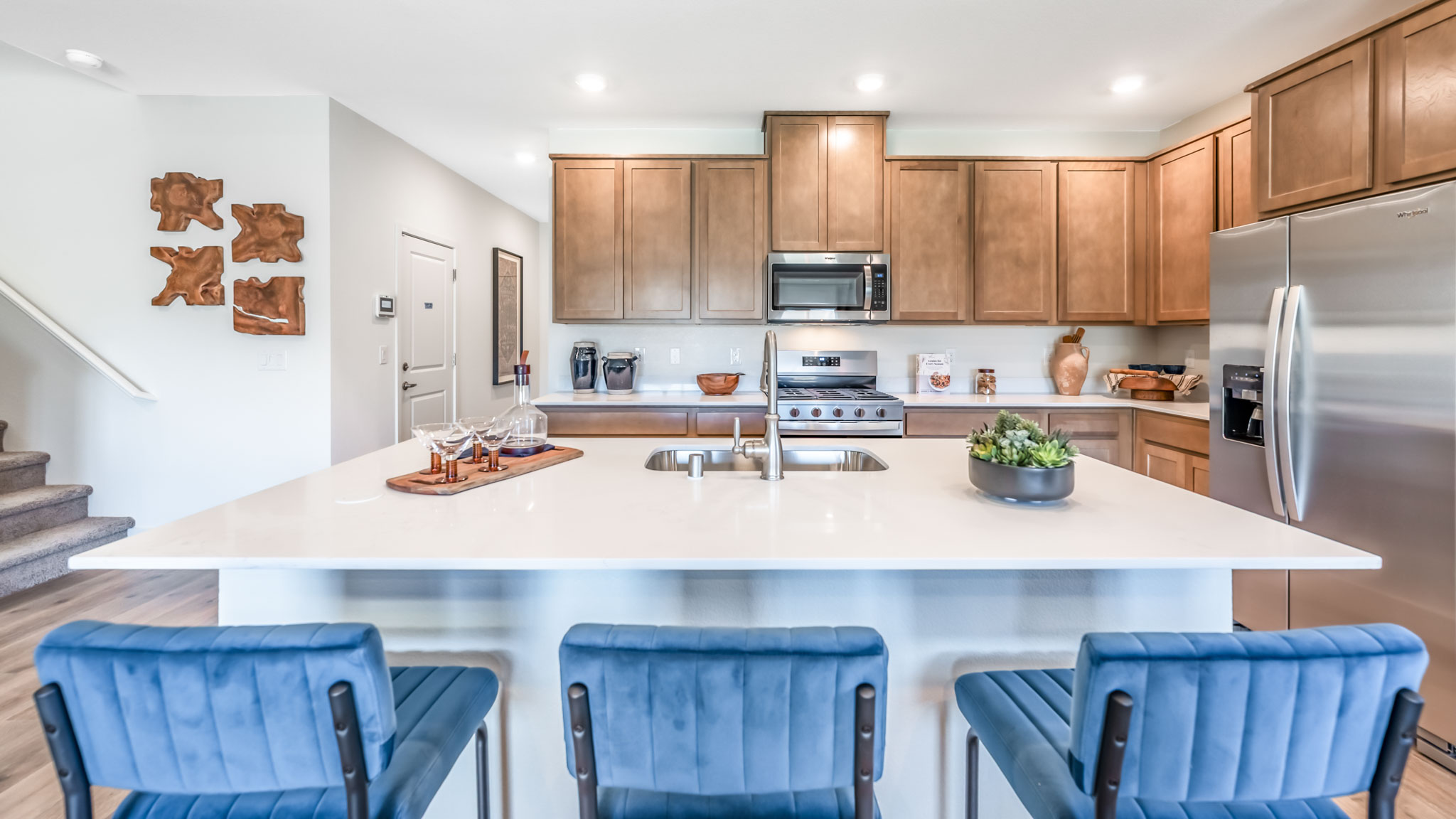 Large kitchen island with space for three barstools separating kitchen area from the rest of the open-concept first floor