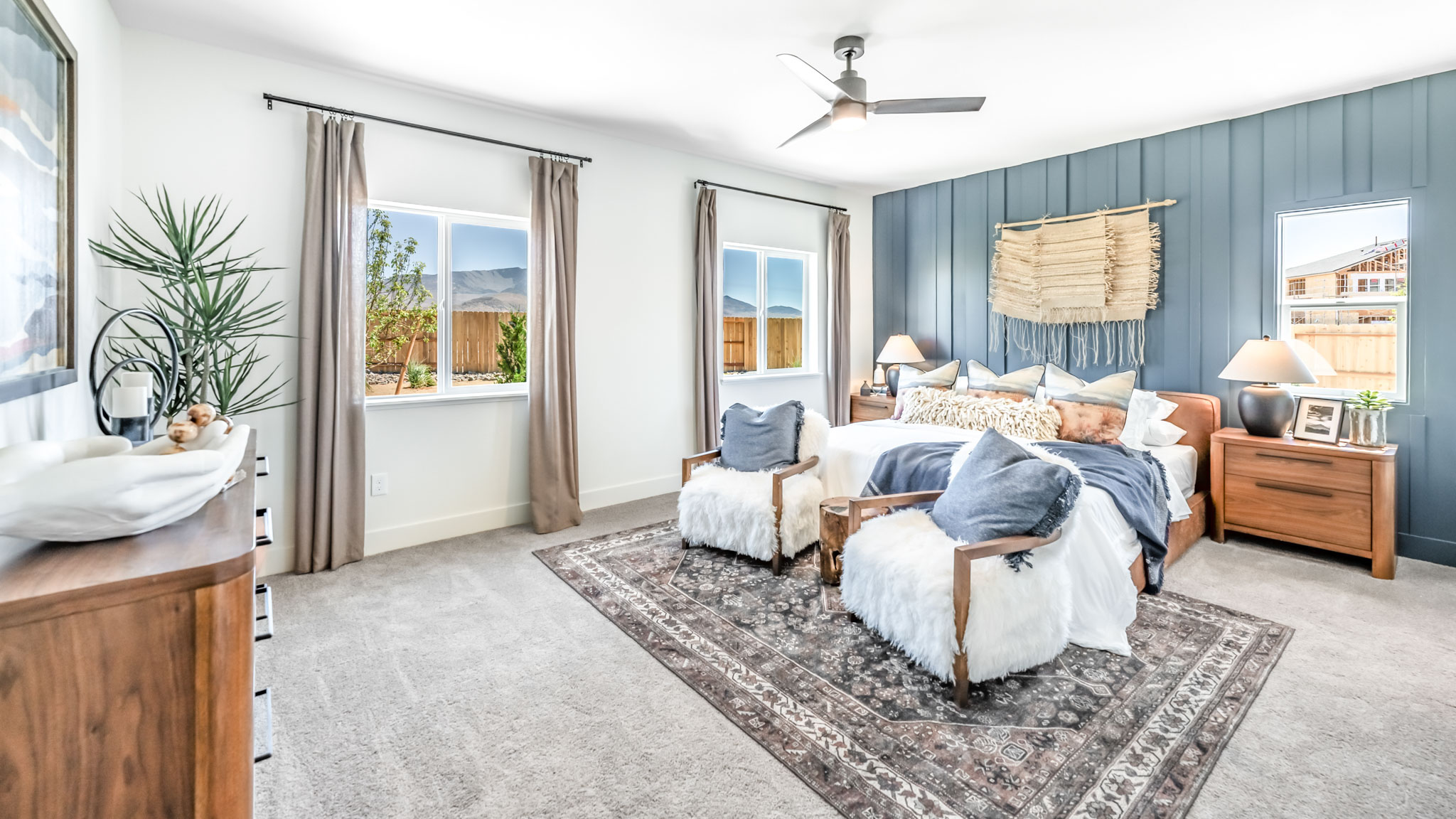 Large primary bedroom on the first floor with carpeted floor and big windows to let in natural light
