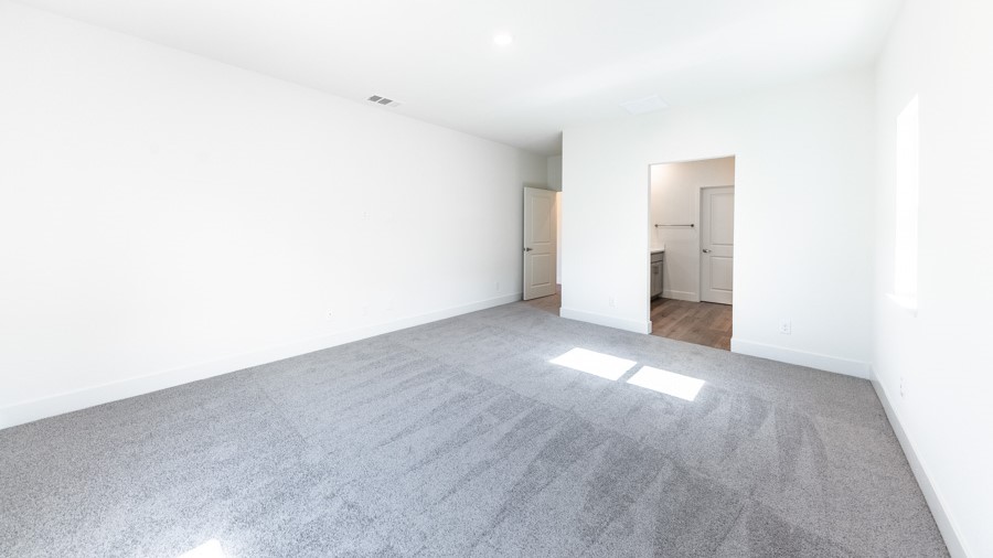 Primary bedroom with carpet looking into the bathroom