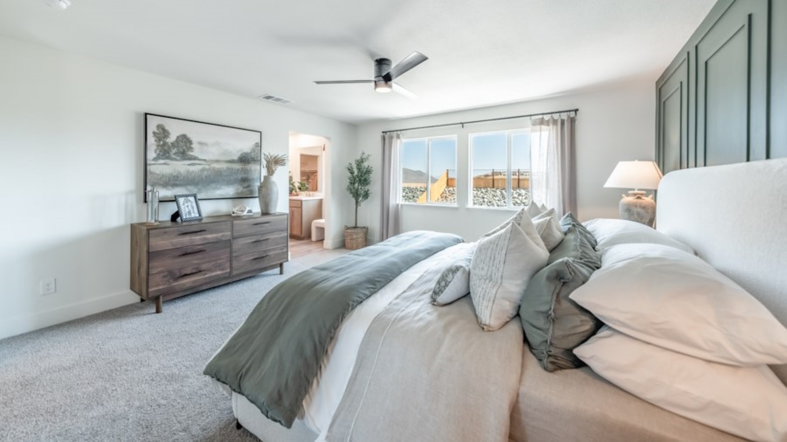 Carpeted primary bedroom with large windows and attached bathroom