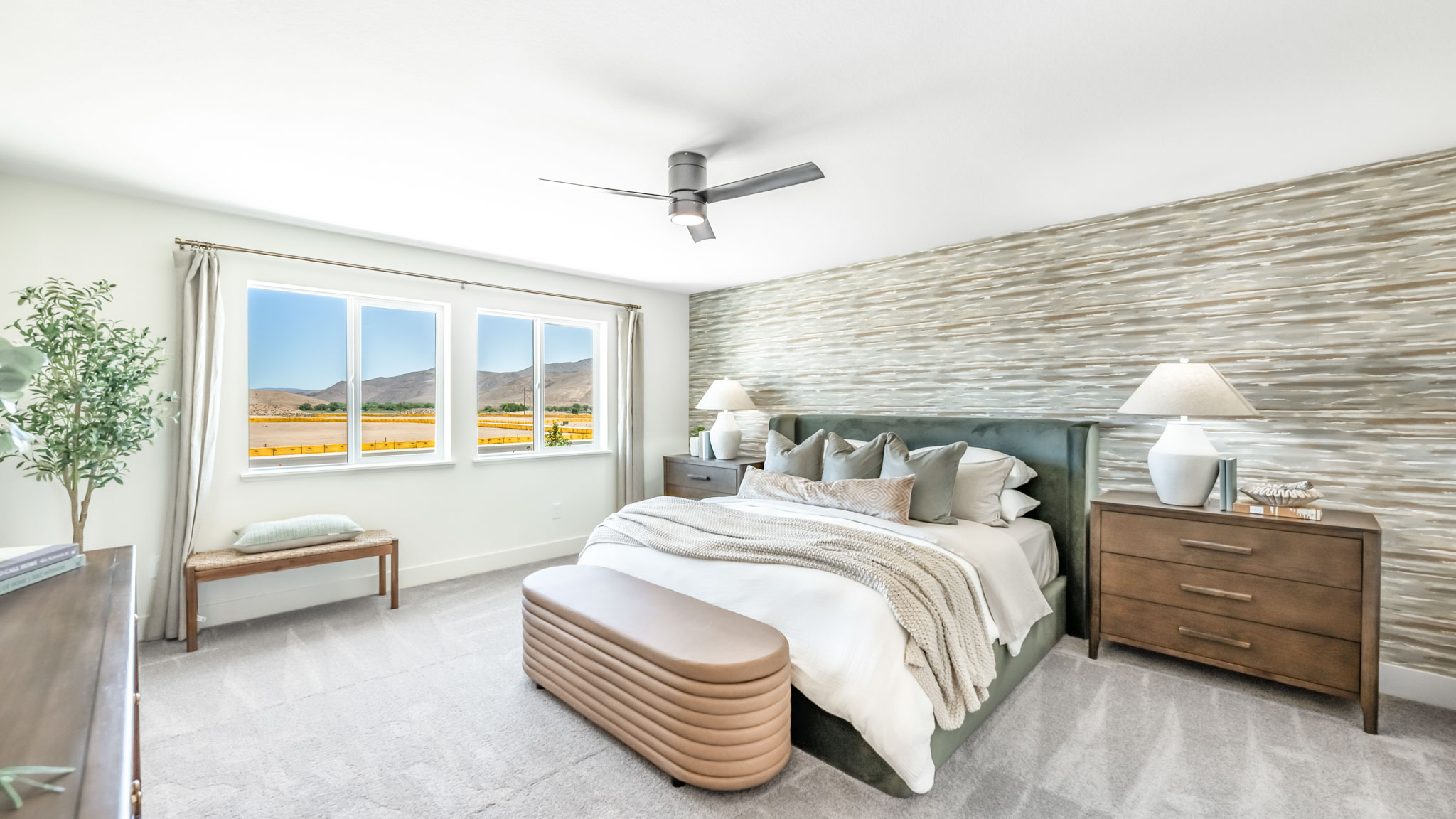 Large primary bedroom with carpeted floor and big windows to let in natural light