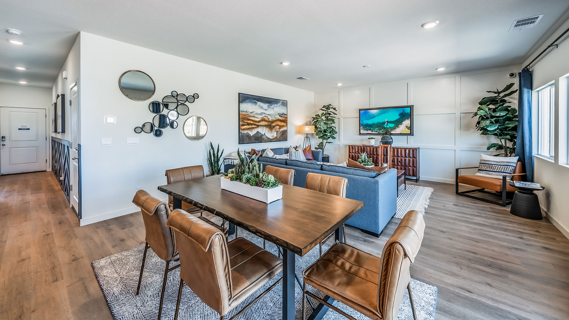 Dining table next to living room with large bright windows
