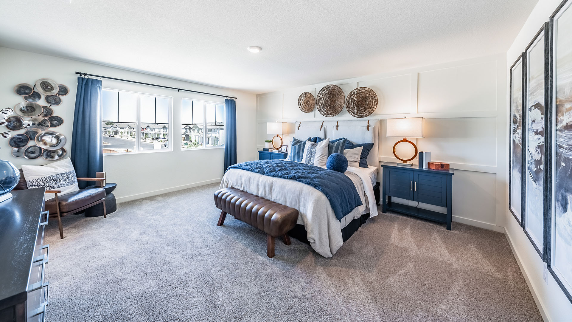 Large primary bedroom with carpeted floor and big windows to let in natural light