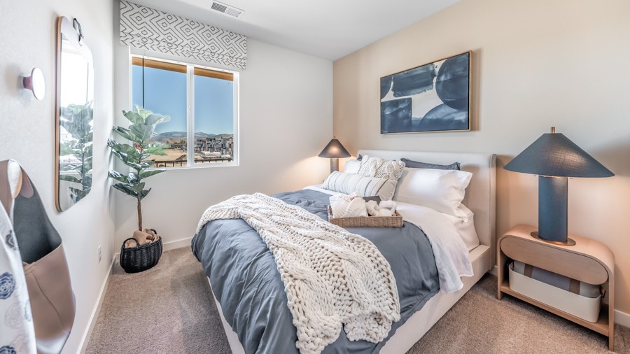 Bedroom with large window letting in bright light and carpeted floors
