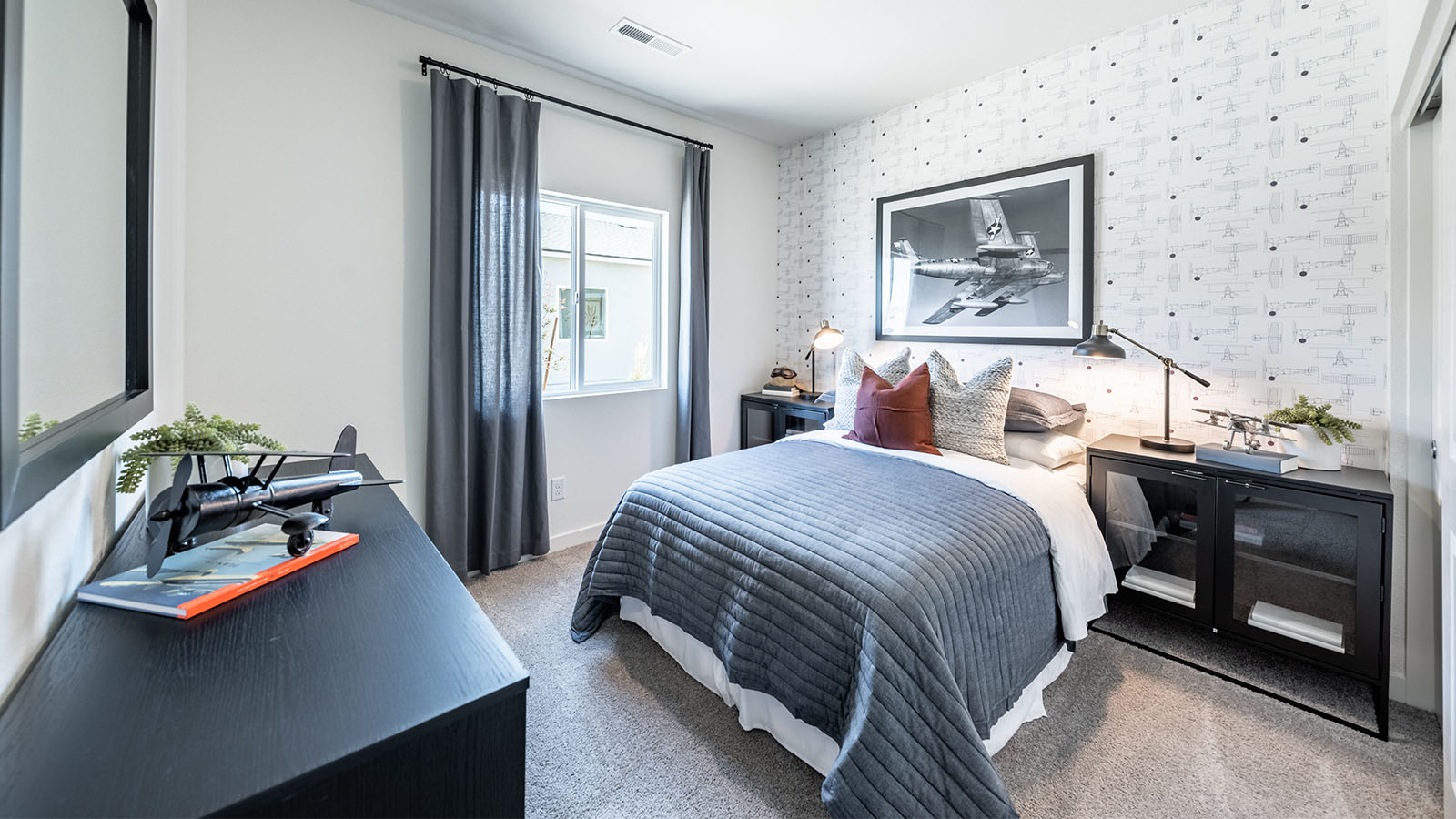 Secondary bedroom with carpet and a large window at the front of the home