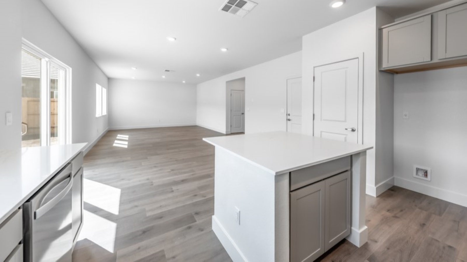 Kitchen island with built-in sink and dishwasher looking out onto dining and living area