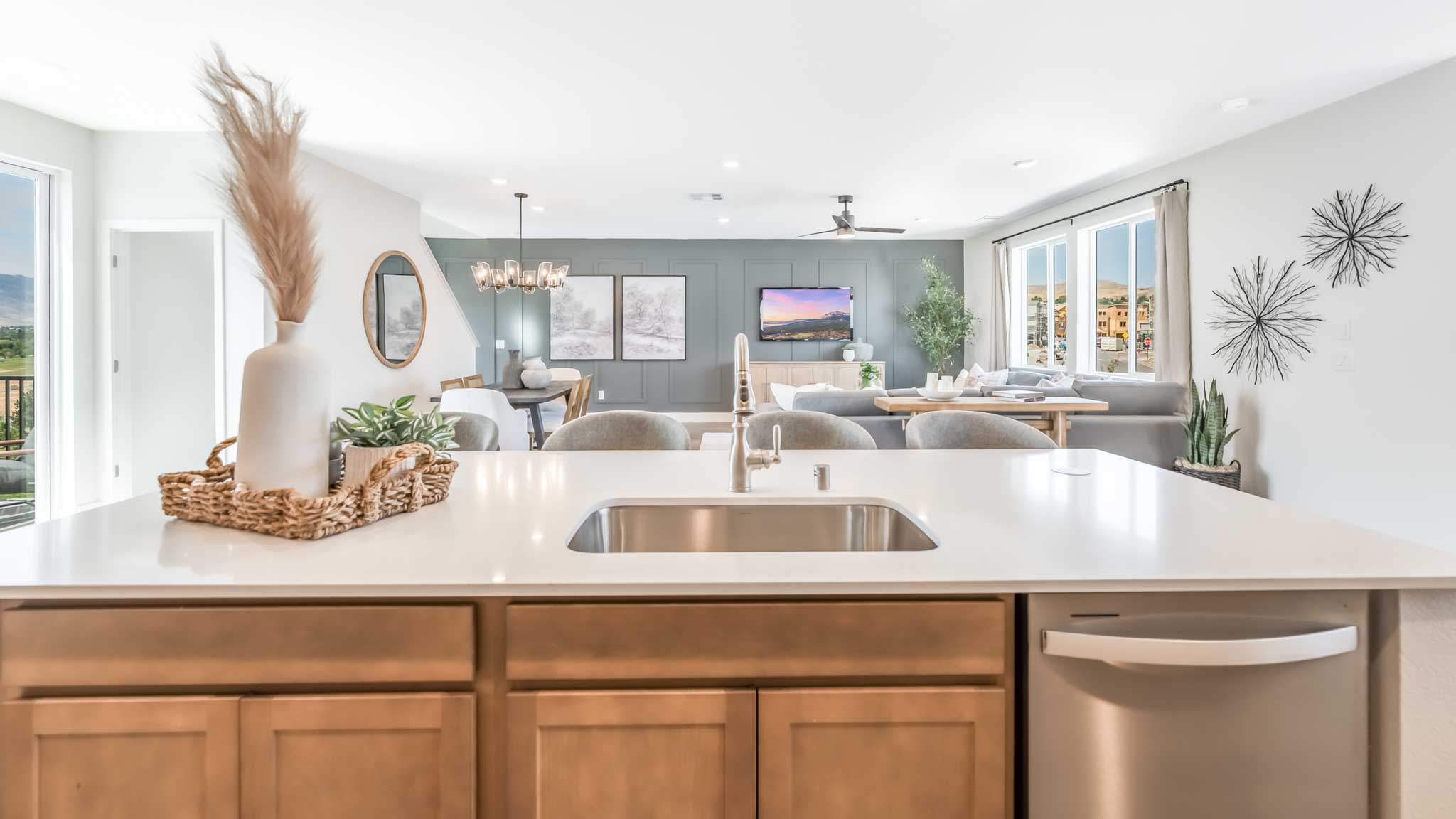 Kitchen island with a single basin sink and dishwasher facing the great room