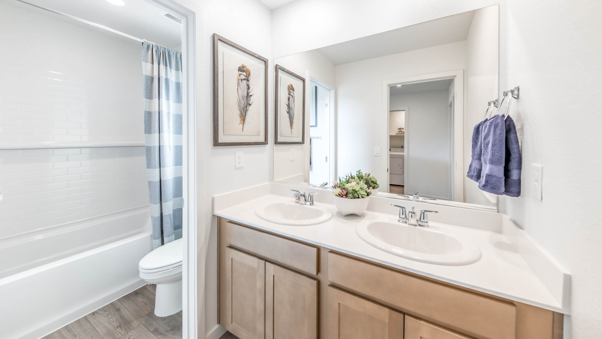 Secondary bathroom with dual sinks and a separate area for toilet and shower tub combo