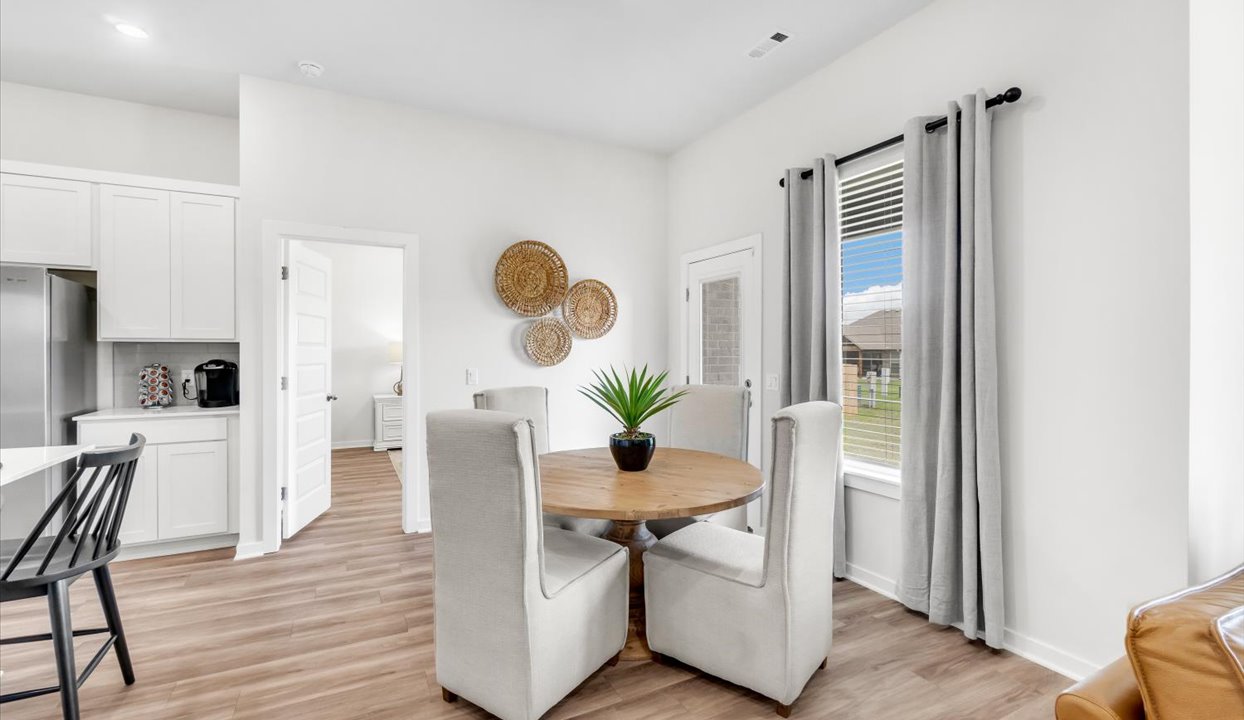 Dinning room area with large window, door leading into bedroom and then door to the right leading to outside patio.