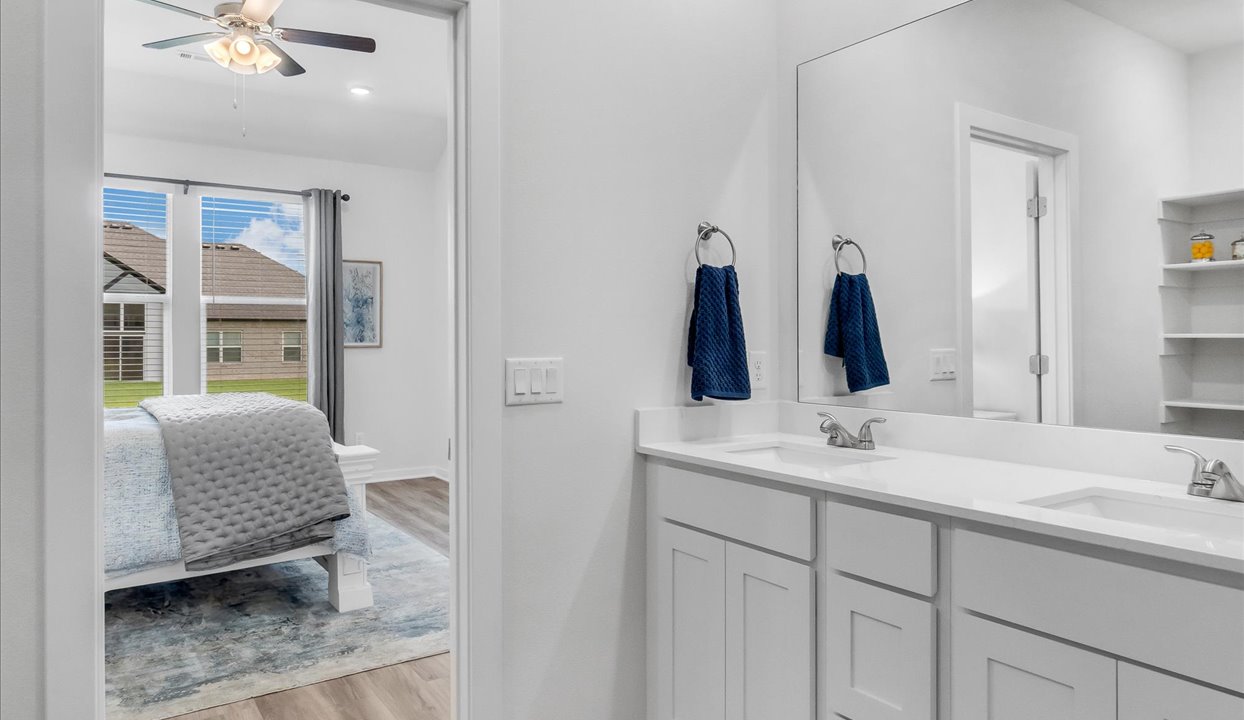 Master bathroom featuring  double stinks and door leading into bedroom.