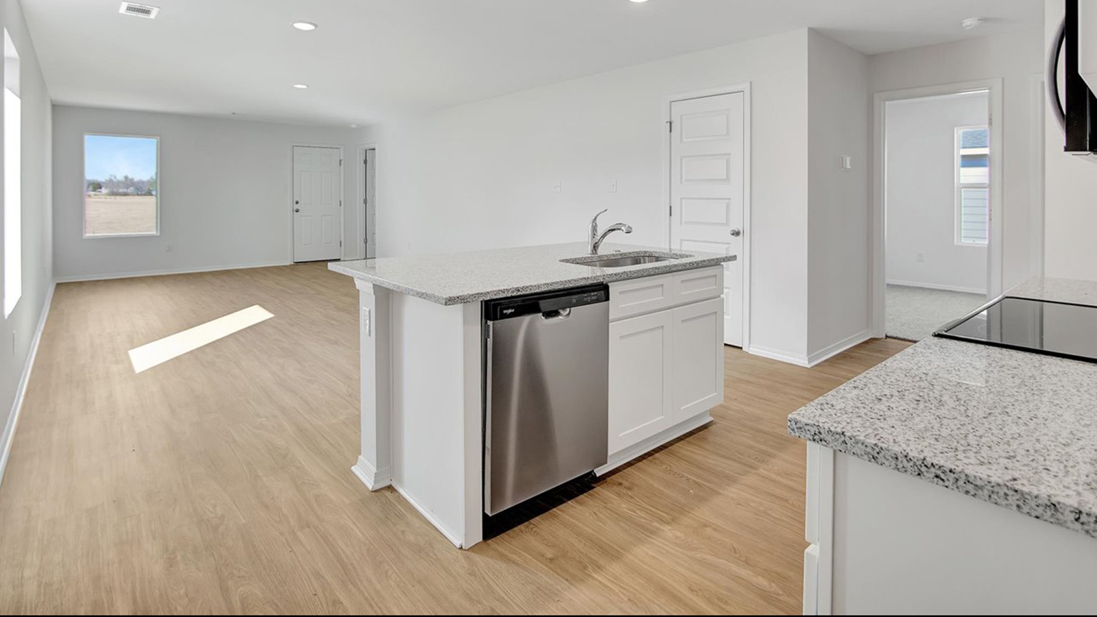 Kitchen with white cabinets and island open to living area