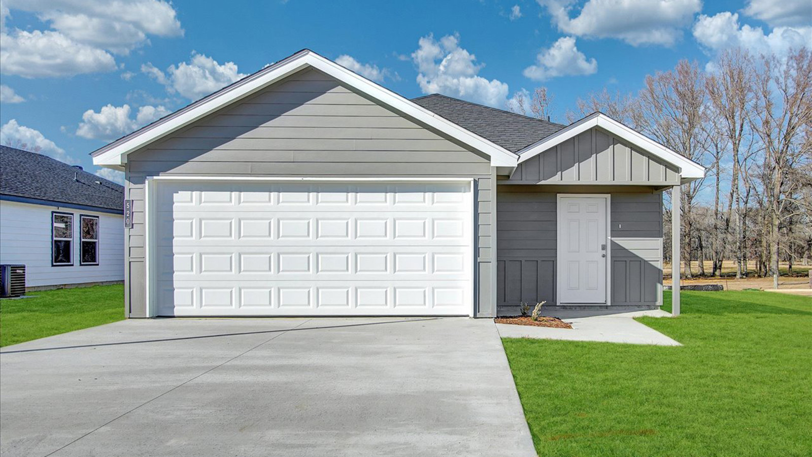 Single story home with gray siding and white two car garage