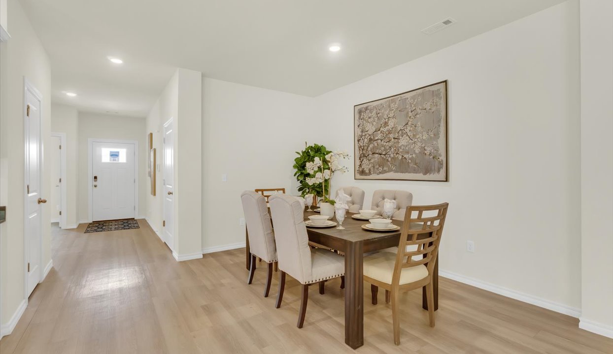 Open concept living space featuring  dinning room with hallway leading into front door.