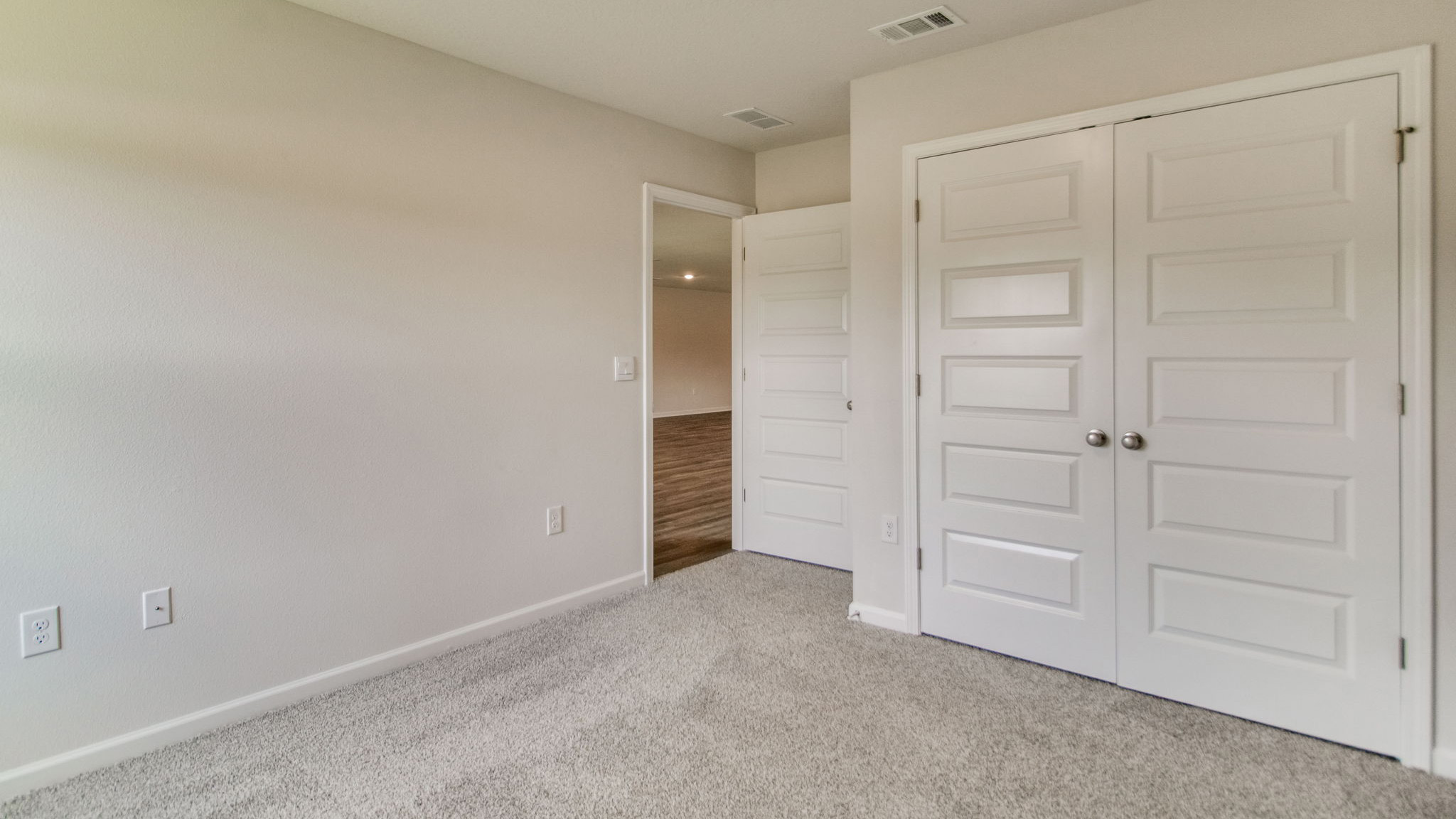 The Sawyer floorplan guest bedroom one with carpet throughout