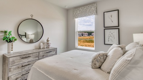 The Palm floorplan primary bedroom with three windows and natural lighting