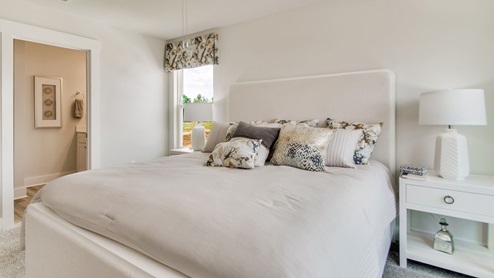 The Palm floorplan primary bedroom with three windows and natural lighting
