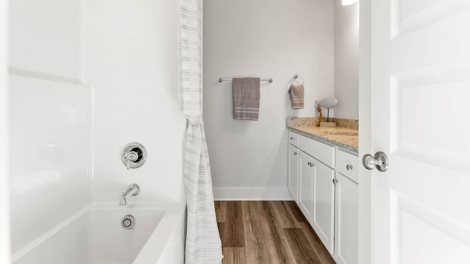 Bathroom with single vanity granite countertops and white cabinets and toilet and shower.